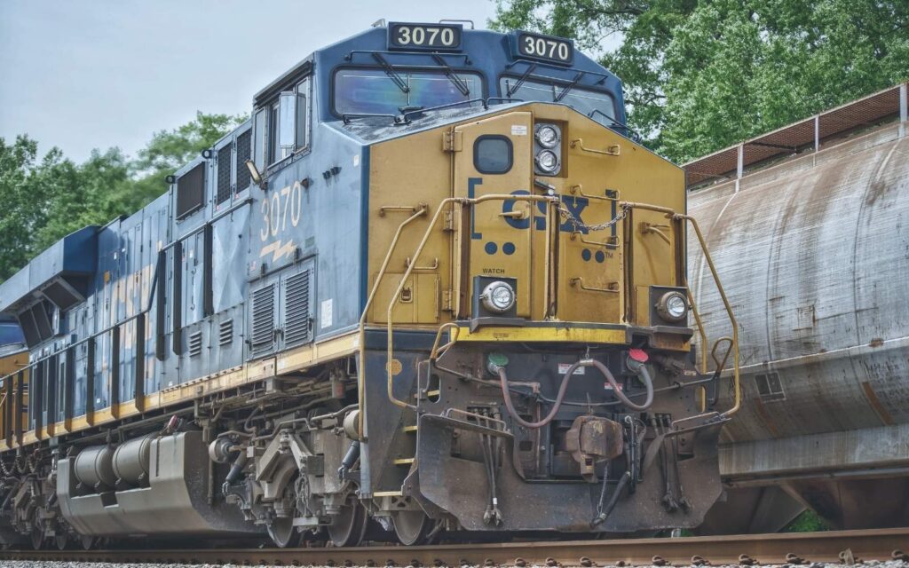 Blue and yellow diesel freight locomotive on tracks beside a wall.