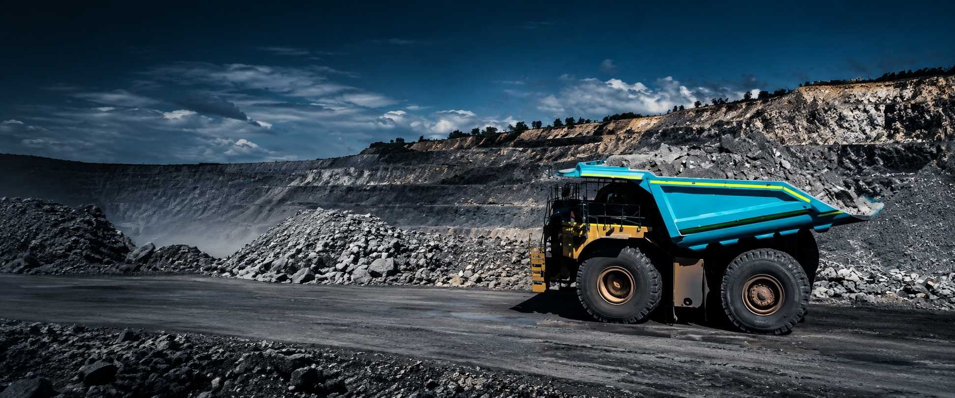 Mining haul truck with a loaded tray driving through an open-cut mine site